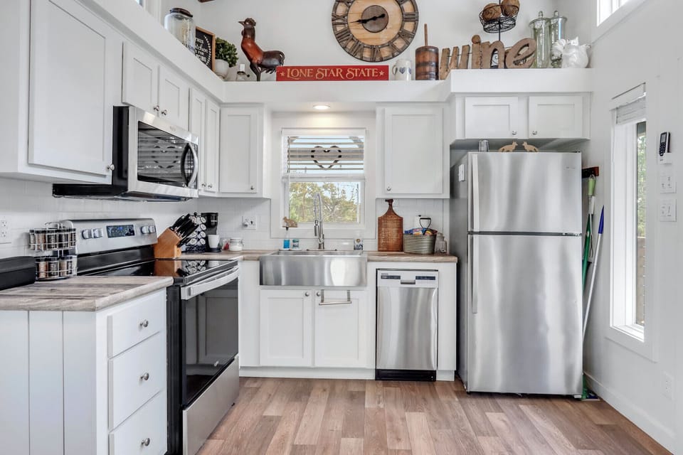 The fully equipped kitchen features modern stainless steel appliances and charming rustic touches