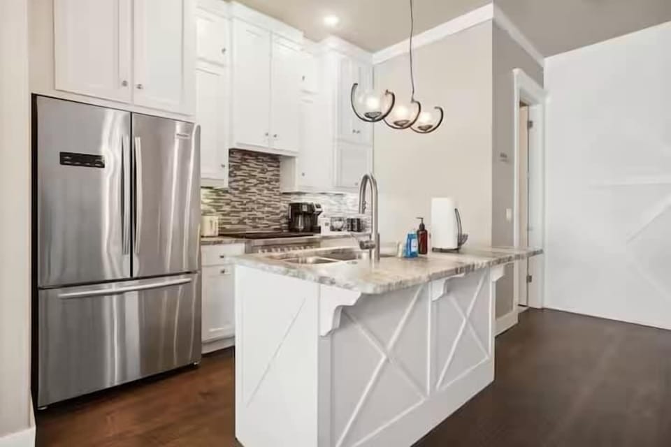 Alternate kitchen view featuring the French-door stainless refrigerator and marble-topped island with seating.