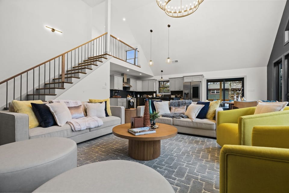 Relax on the sectional sofa near the staircase with natural light streaming through the windows
