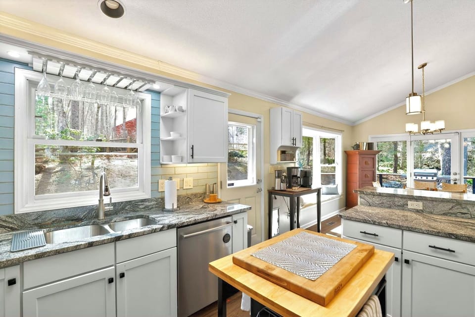 Bright updated kitchen with island, granite counters, and wooded views