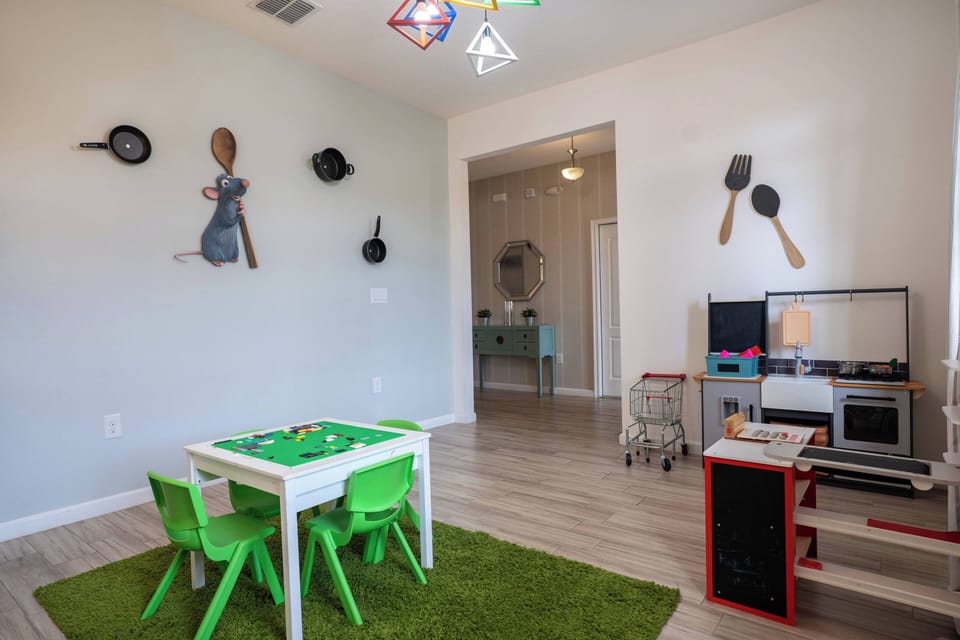Bright and playful, this room offers a cozy play area with vibrant green chairs and a delightful table for kids. Stylish kitchen-themed decor adds whimsy, while the light-filled layout creates an inviting and warm atmosphere.