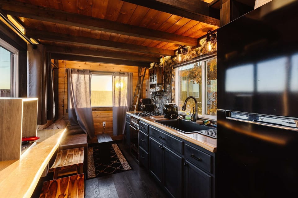 Fully equipped kitchen with wood countertops, modern appliances, a gas range, and stylish cabinetry. Bright windows and thoughtful design make cooking easy, functional, and enjoyable in this cozy tiny home.