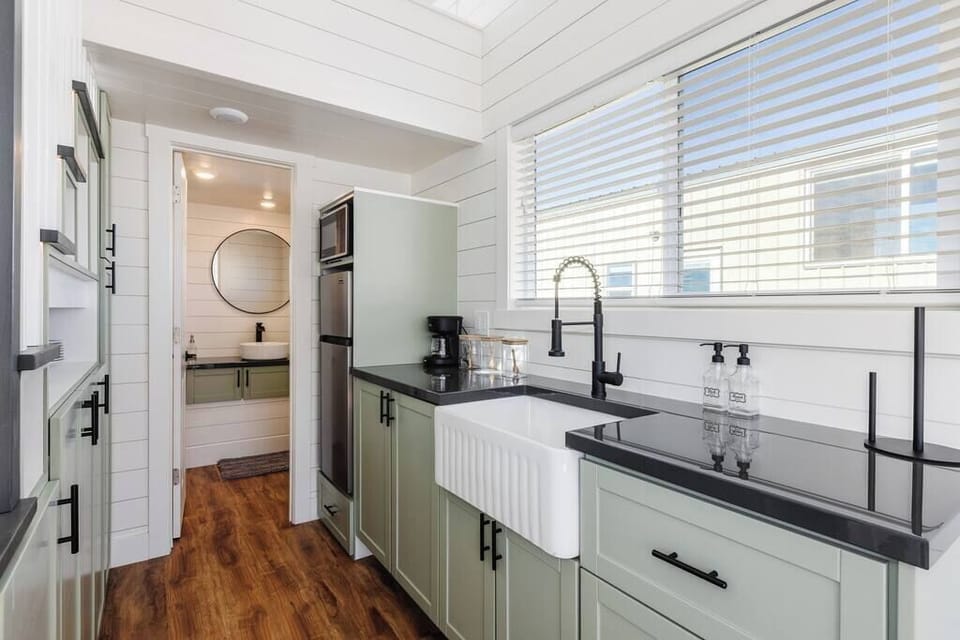 The kitchen is fully equipped with a refrigerator, freezer, microwave, cooktop, and sink with hot/cold water. Enjoy coffee from the coffee maker and ample counter space. Essentials include cookware, dishes, utensils, and plenty of storage cabinets.