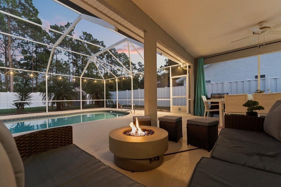 Outdoor lounge area with fire pit and screened pool views, ideal for unwinding after a day at the beach.