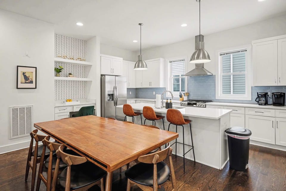 Bright dining and chef’s kitchen with island seating, pendant lights, and coffee bar.