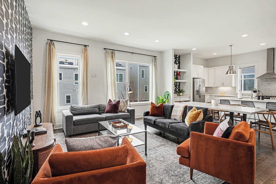 Open-concept living room with plush seating, large windows, and a chef's kitchen.