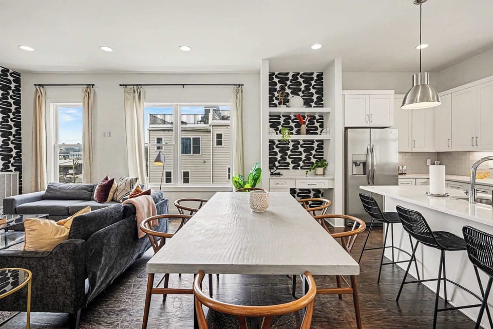 Bright dining and chef’s kitchen with island seating, pendant lights, and coffee bar. | Unit A