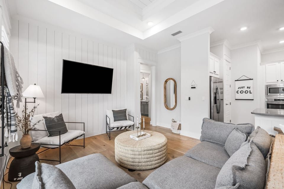 Bright and airy open-concept living space with comfortable seating, natural light, and serene forest views.