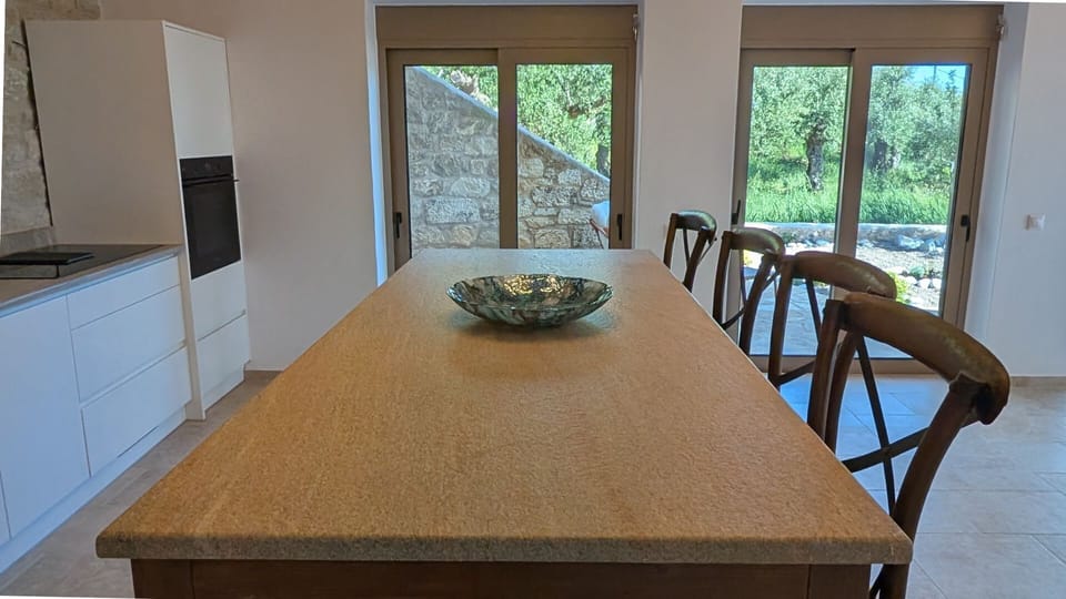 Stone-topped kitchen island with bar seating at Achilles Cottage opening onto the Mani garden courtyard