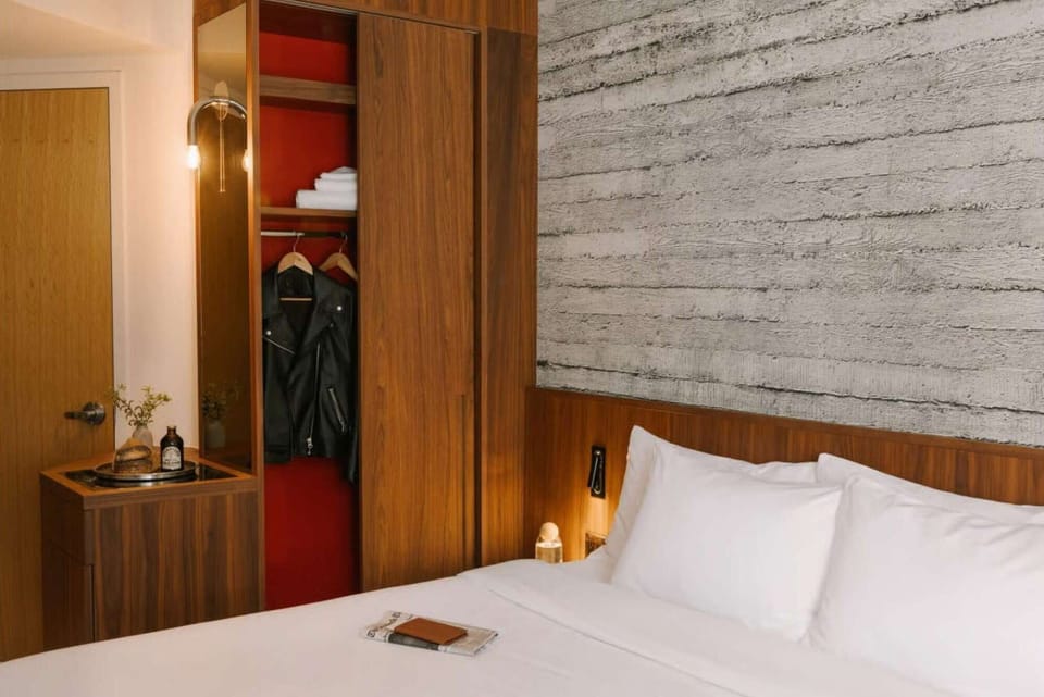 Bedroom corner with open wardrobe, folded linens, and bedside tray