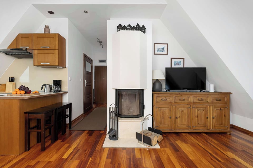 A studio-style living area with a TV, wooden cabinet, and small kitchen corner. The open layout makes the room feel practical and functional.