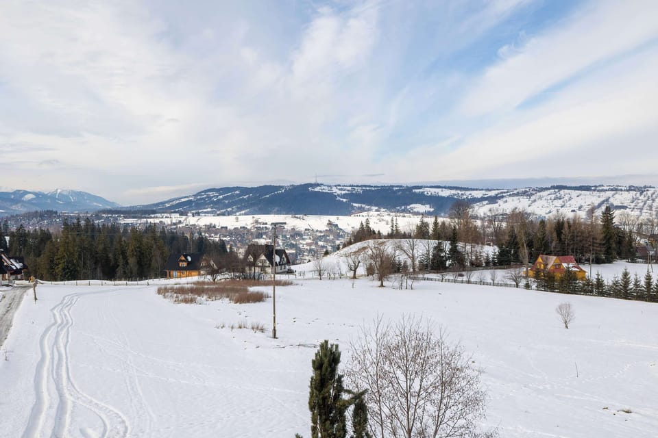 A wide snowy landscape with rolling hills and distant mountains. The scene looks peaceful and natural, typical of a winter countryside view.
