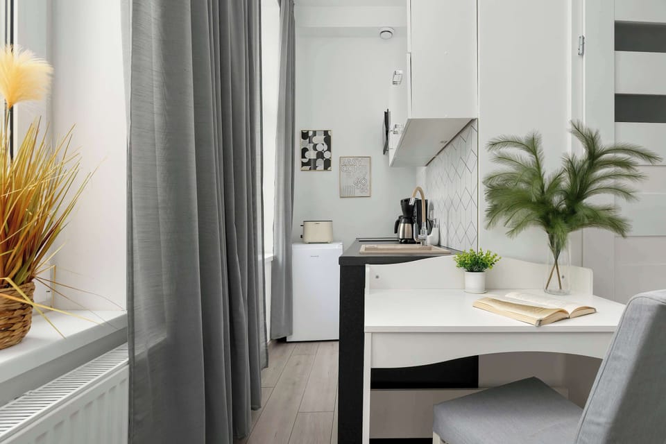 A small, bright workspace by the window with a clean desk and a decorative plant. Perfect for working or studying in natural light.