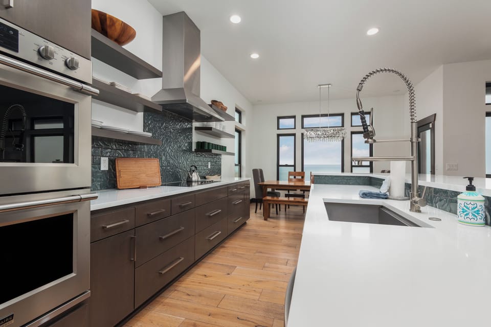 Your sleek modern kitchen features professional-grade appliances, pristine white countertops, and stunning dark green tile backsplash for effortless meal preparation.