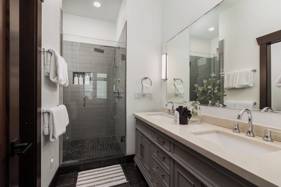 Unwind in your spa-like bathroom featuring a glass-enclosed shower, dual vanities, and plush towels—perfect for refreshing after your adventures.