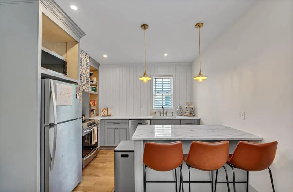 Fully stocked kitchen with quartzite countertops and stainless steel appliances.