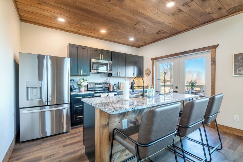 Cook together in your fully equipped gourmet kitchen featuring granite counters, stainless steel appliances, and rustic wood beam ceiling—perfect for memorable meals.