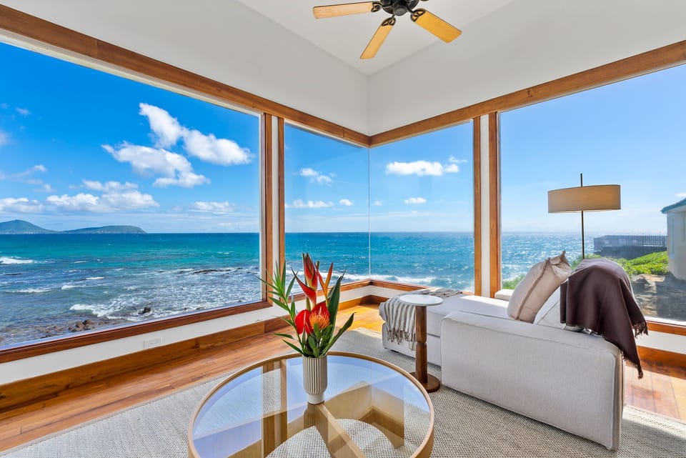 Unwind in your oceanfront sanctuary where floor-to-ceiling windows frame endless sea views and comfortable seating invites relaxation.