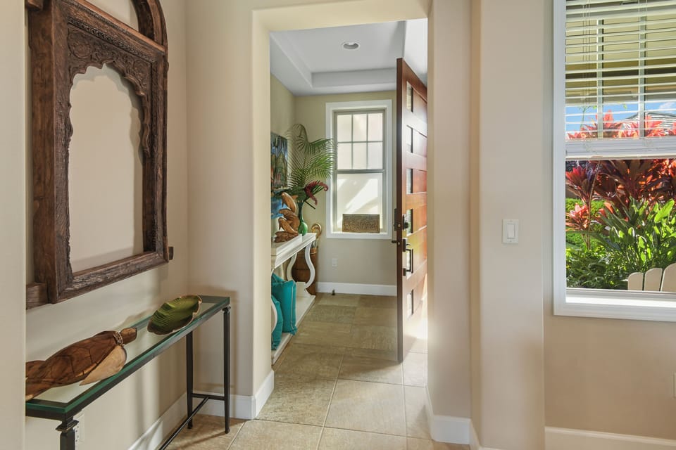 Step into your welcoming entryway, where natural light streams through windows revealing tropical gardens beyond your doorstep.
