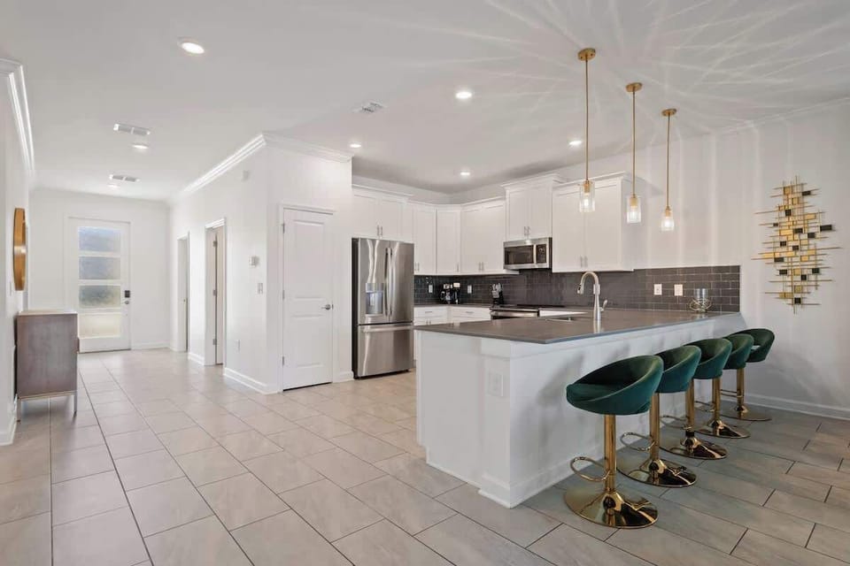 Step into this stunning kitchen, designed for both style and functionality. With sleek countertops, modern appliances, and gold-accented bar stools, it's perfect for preparing meals while enjoying each other's company.