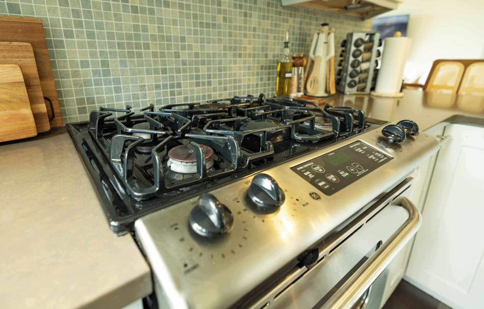 A modern gas cooktop with sleek controls and a tiled backsplash offers a functional and stylish space to prepare everything from quick breakfasts to home-cooked dinners