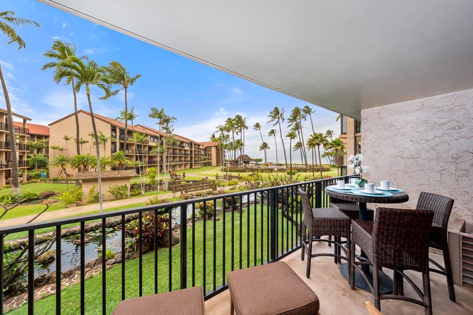 Private lanai with cushioned seating with ocean views, lush tropical gardens and resort pathways, ideal for enjoying morning coffee or sunset moments.