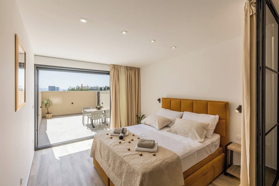 Bedroom with balcony access, filled with natural light and soft warm tones.
