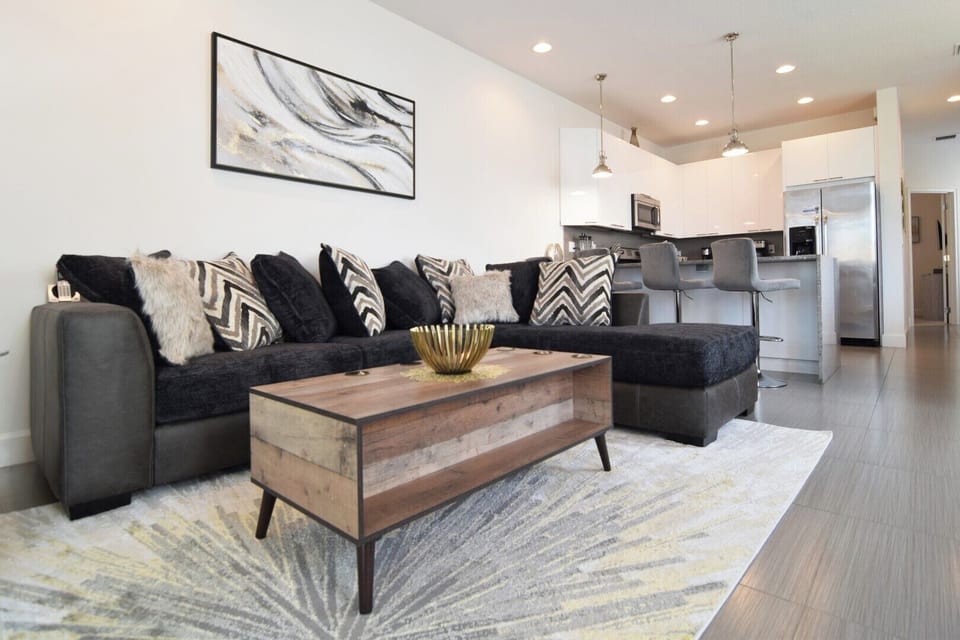 Beautiful lounge area with L-shaped sofa, 75-inch Smart TV, doors to pool deck
