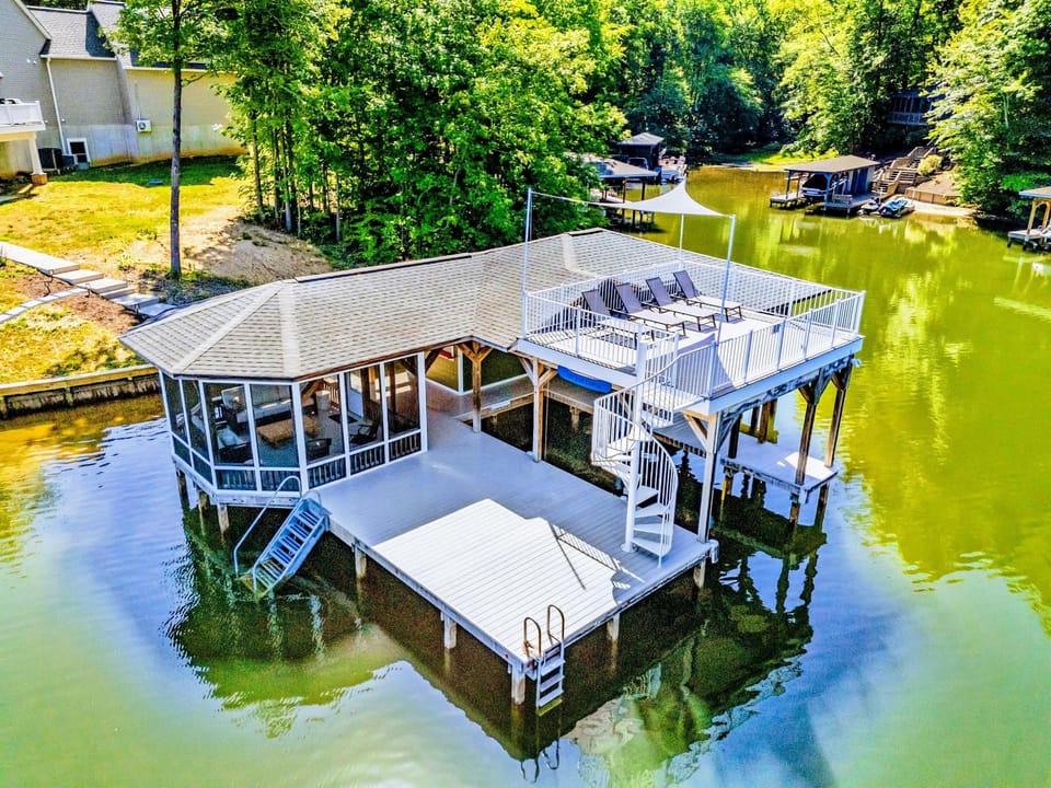 Boathouse - Covered slip below and a rooftop sun deck above, with lounge chairs and open water wrapping around three sides.