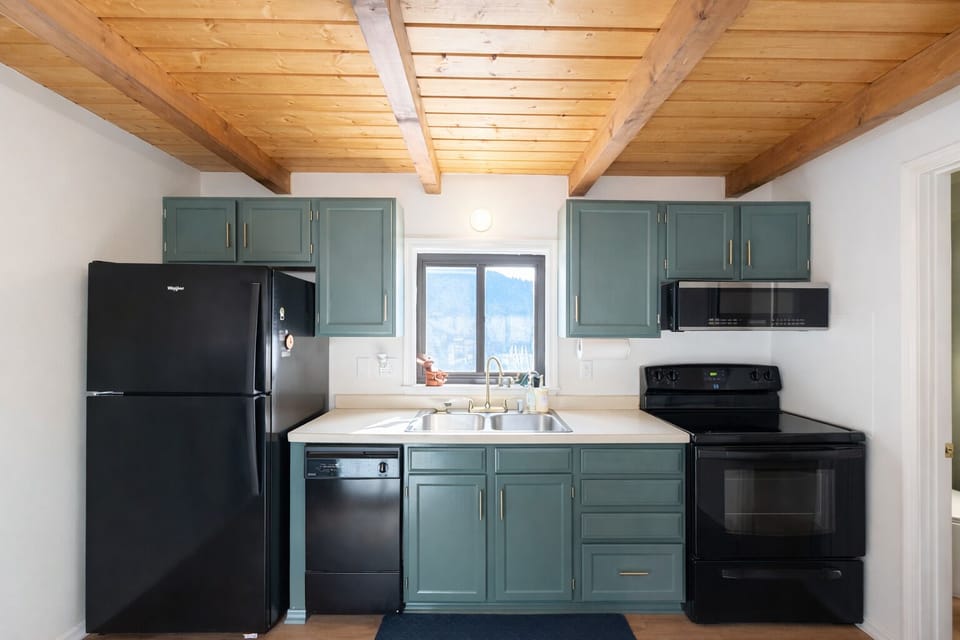 Cozy kitchen with rustic beams, stylish cabinets & full black appliances