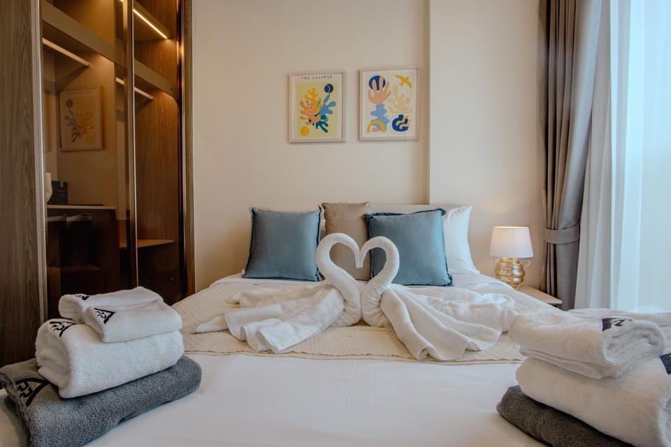 Comfortable bedroom with a large bed, soft linens, accent pillows, and decorative towel arrangement.