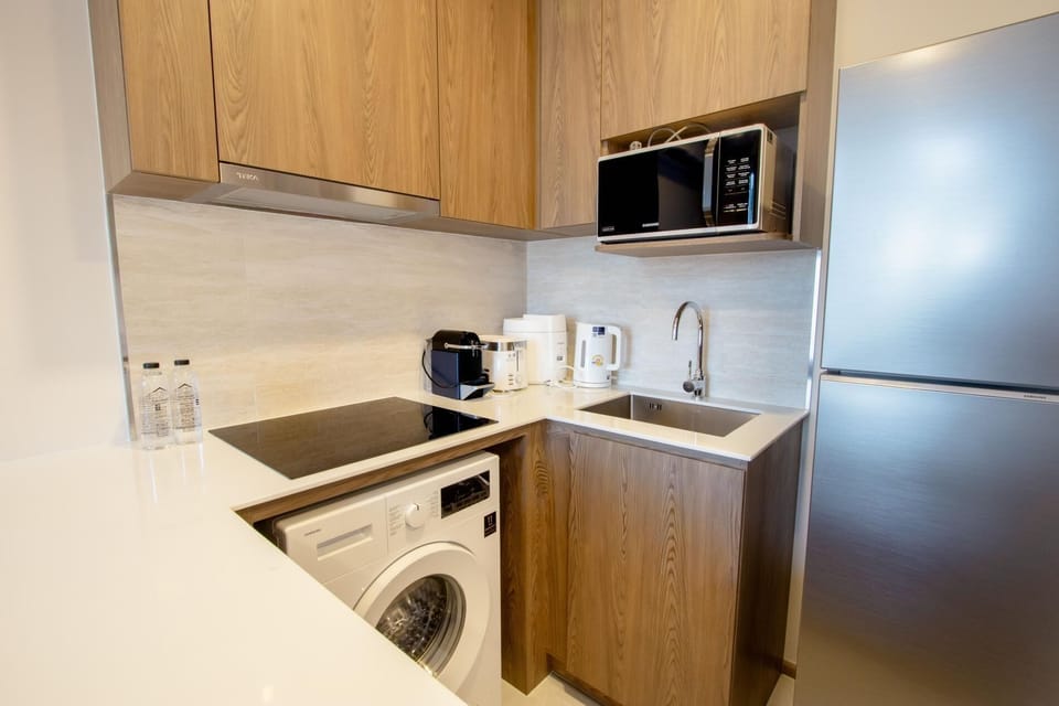 Compact modern kitchen with stovetop, microwave, refrigerator, and essential cooking amenities.