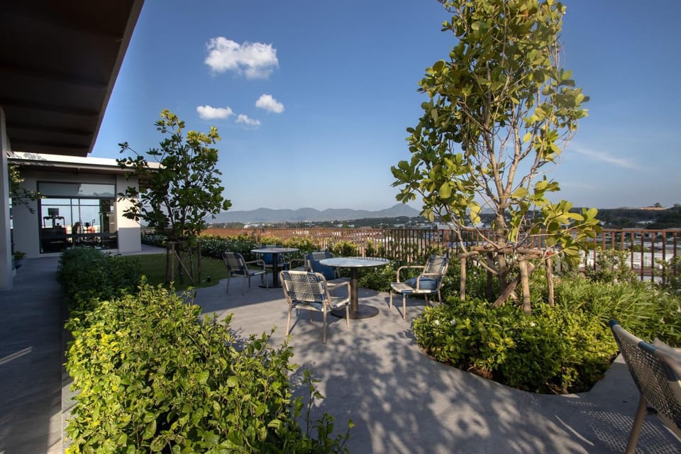 Open-air rooftop terrace featuring seating, greenery, and panoramic city views.