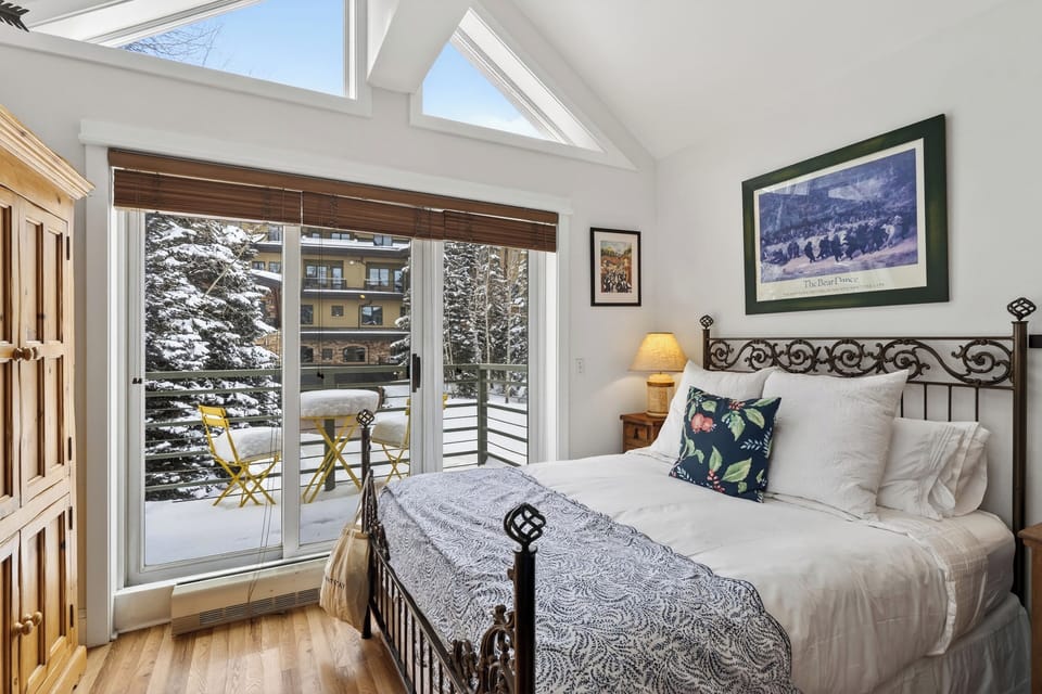 Sun-drenched studio bedroom featuring vaulted ceilings and a private balcony with snowy views.