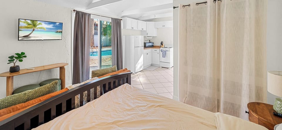 GUEST HOUSE Bedroom Oasis: Sun-drenched space with kitchen access and a view of the inviting poolside!