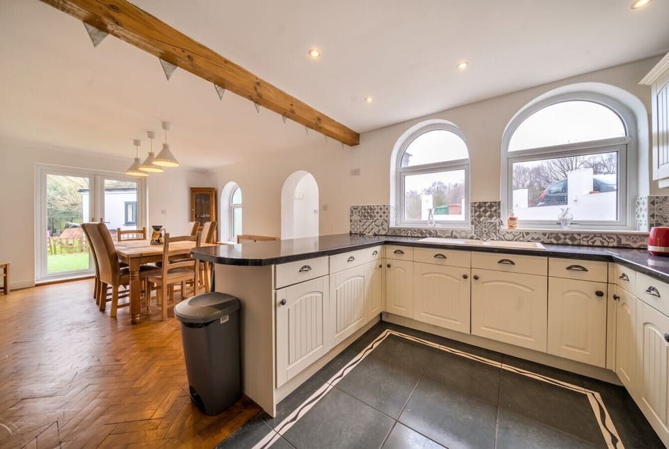 Open-plan kitchen with cream units and arched windows framing the garden.