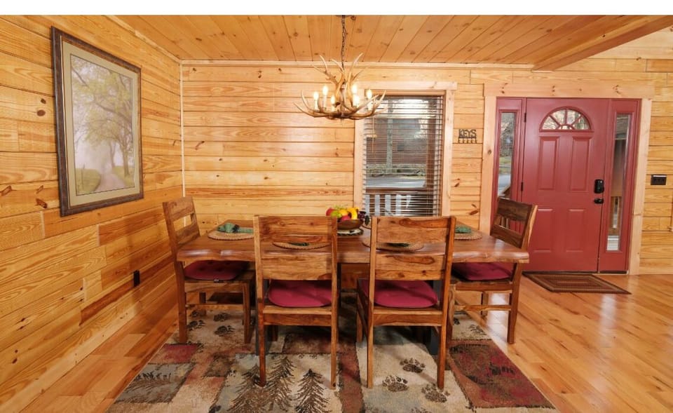 Gather around your rustic dining table under the warm antler chandelier, where wood walls create a cozy cabin atmosphere for memorable meals together.