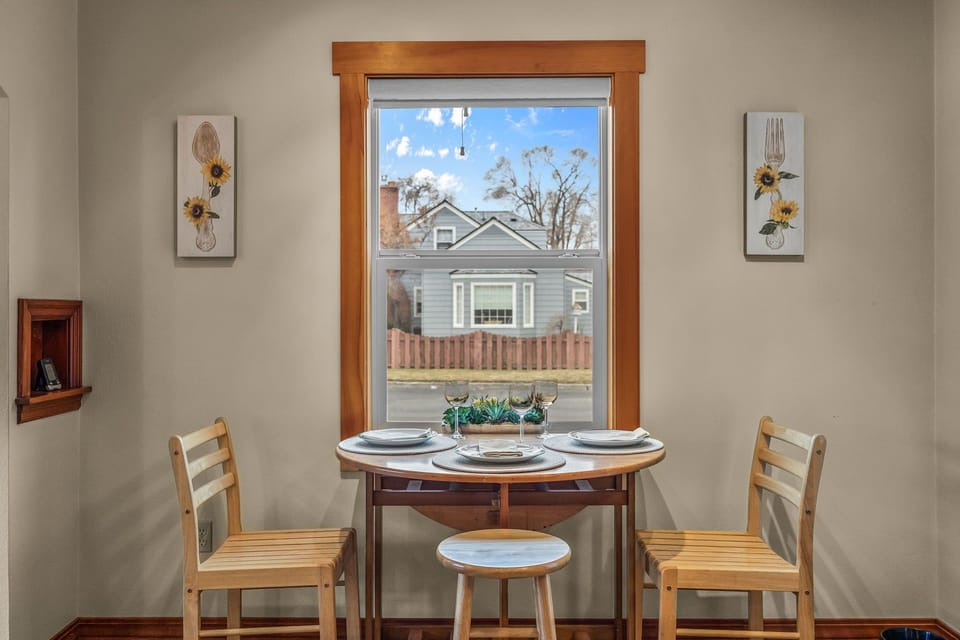 Enjoy intimate meals at your charming window-side table, where natural light streams in and cheerful sunflower artwork creates a warm, welcoming atmosphere.