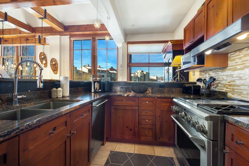 Your gourmet kitchen awaits with granite counters, premium appliances, and warm wood cabinetry bathed in natural light.