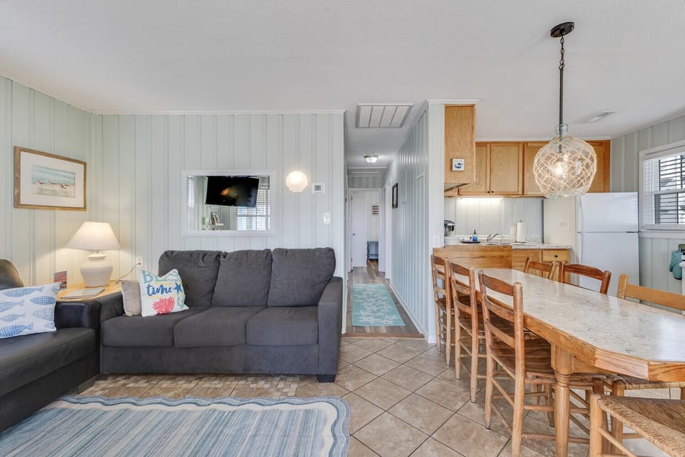 Relax in your bright, coastal-style living space with comfortable seating, full kitchen, and charming nautical touches that create the perfect beach getaway atmosphere.