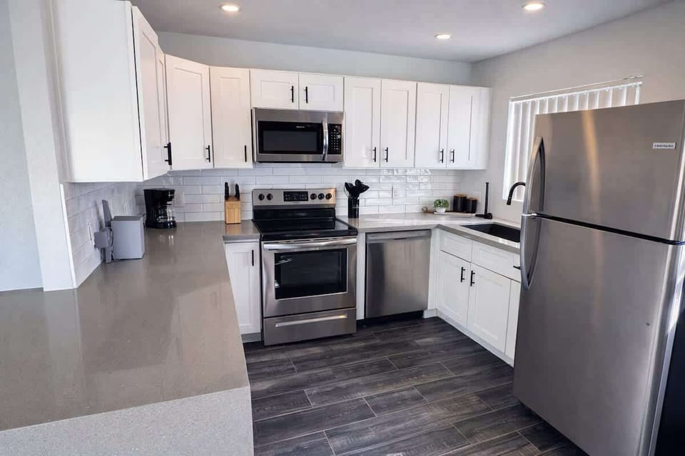 Fully equipped kitchen featuring stainless steel appliances, bar seating for 1 guest, and a dining area.