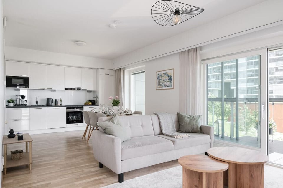 Bright and inviting open-plan living area featuring a modern kitchen, comfortable sofa, and stylish dining space.