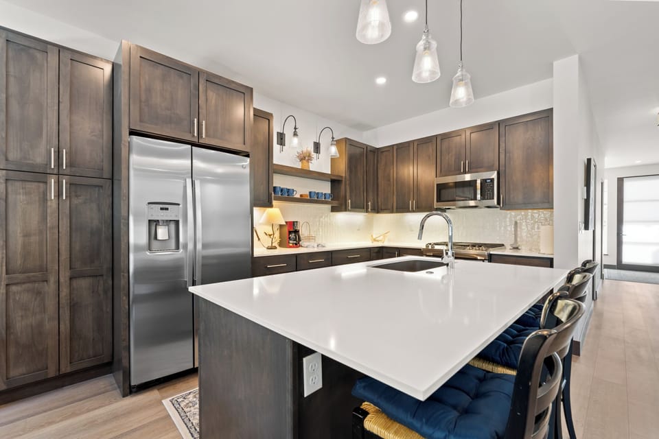 Full kitchen with stainless steel appliances and breakfast bar with seating for three.
