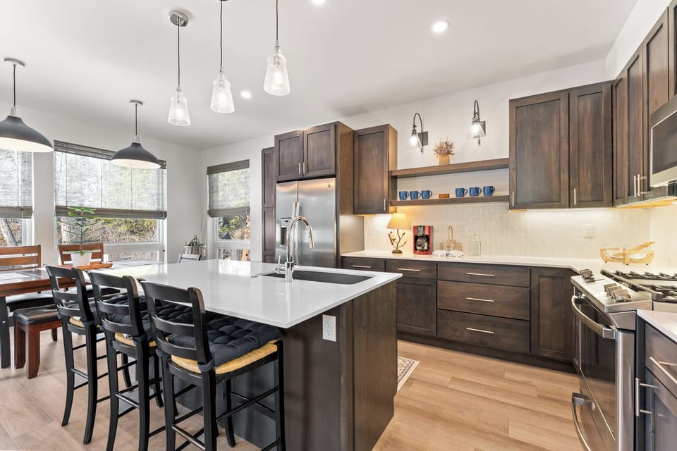 Full kitchen with stainless steel appliances and breakfast bar with seating for three.