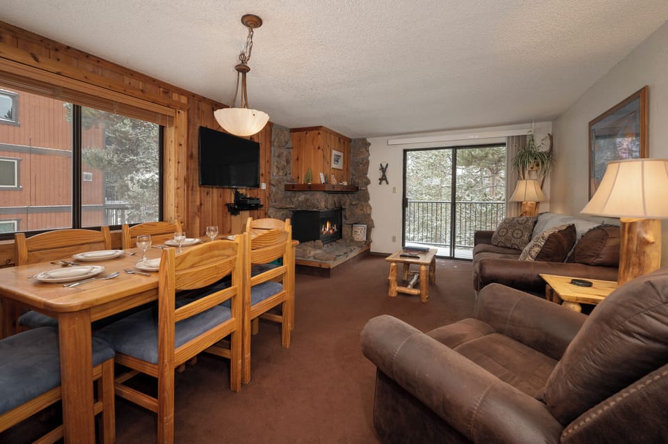 Cozy up by the stone fireplace in your mountain retreat, where warm wood tones and plush seating create the perfect après-ski atmosphere.