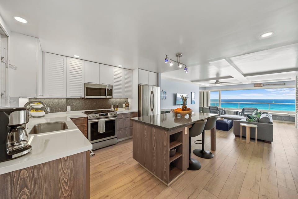 Your open-concept kitchen flows seamlessly into the living space, where ocean views greet you through expansive windows.