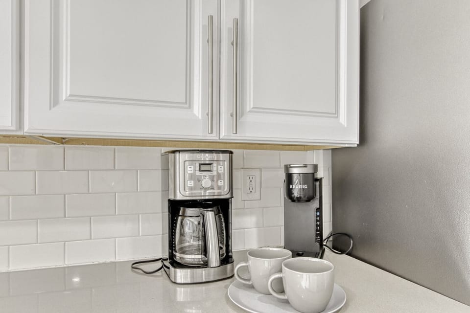 Start your mornings right with premium coffee equipment and fresh mugs waiting for your perfect brew in your sleek kitchen.