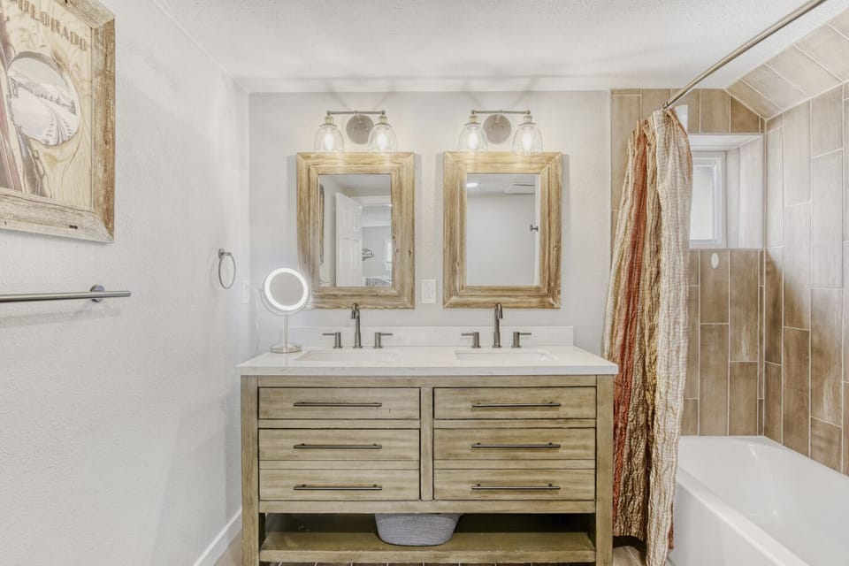 Step into your beautifully appointed bathroom with dual vanity sinks, elegant wood-framed mirrors, and a relaxing tub-shower combo.
