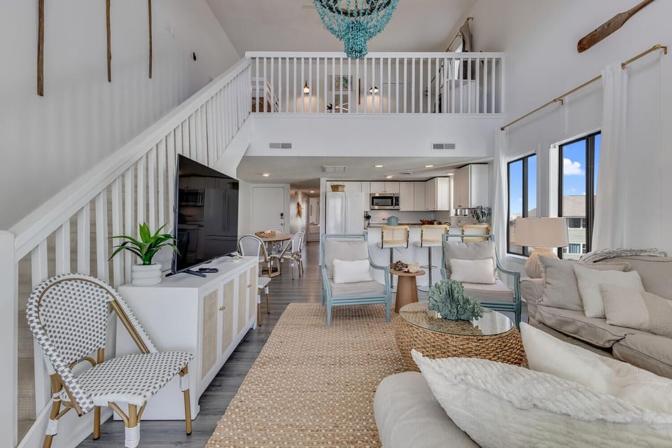 Sink into the plush sofas beneath vaulted ceilings with exposed beams while your turquoise chandelier casts warm light across this open-concept living space.