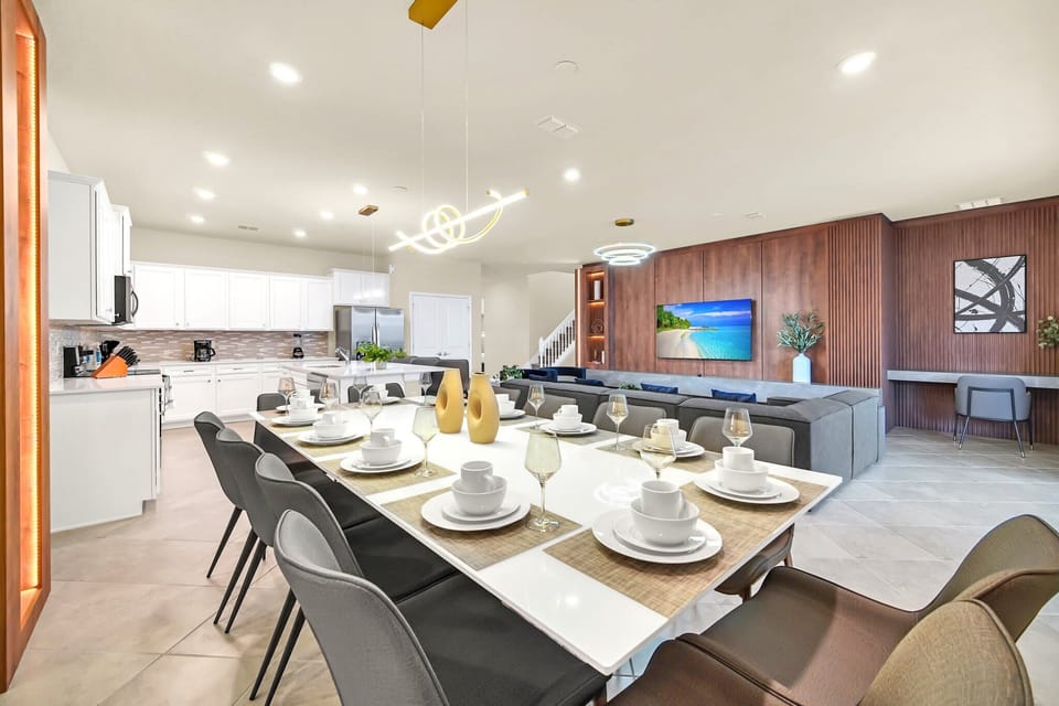 Spacious modern dining area adjacent to a fully equipped kitchen and comfortable living room with a large sectional sofa.